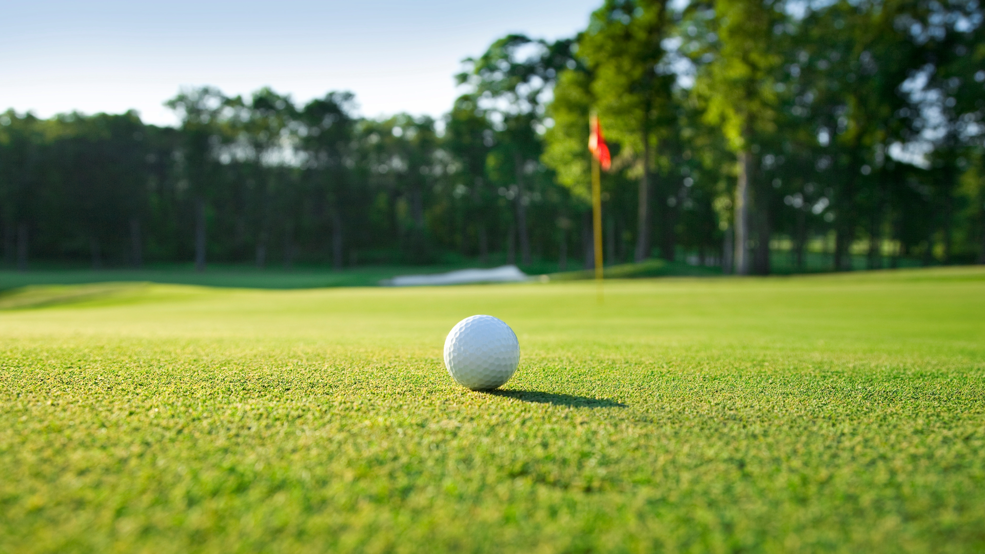 Golf ball on the ground on a golf course with the hole and flagpole in the distance