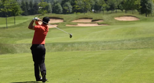 Golfer standing at the end of his swing on golf course