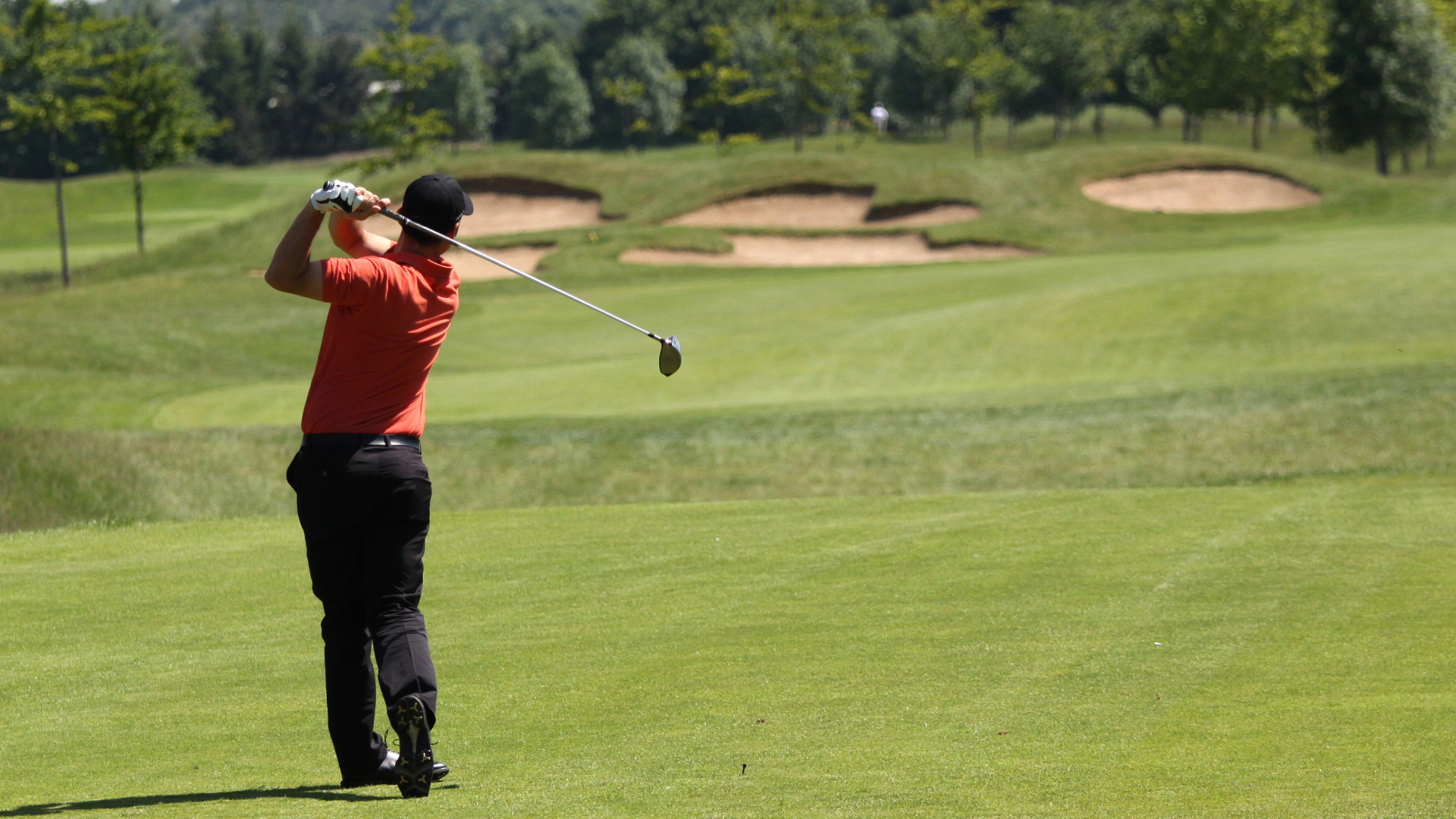 Golfer standing at the end of his swing on golf course