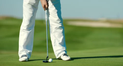 Golfers lower half pictured teeing up to a ball