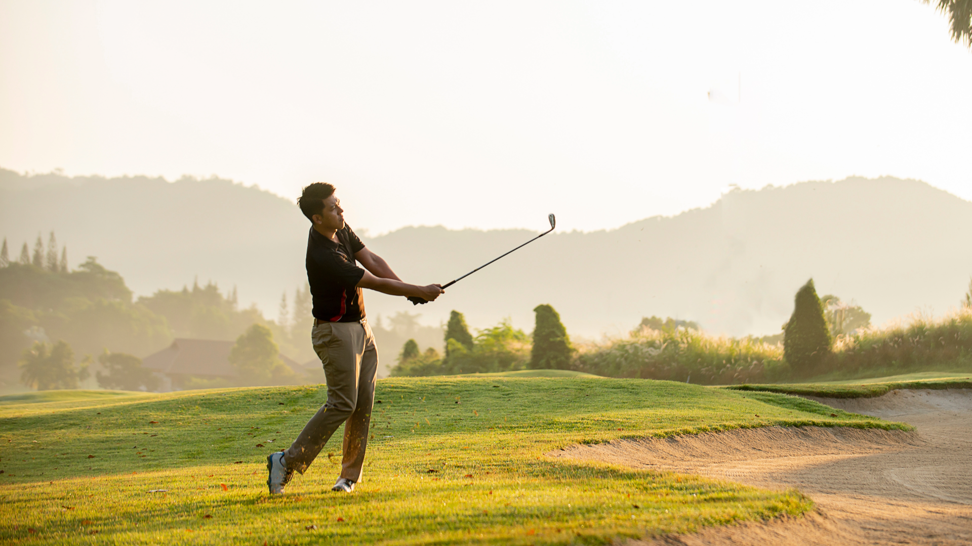 Golfer swinging his club on the golf course