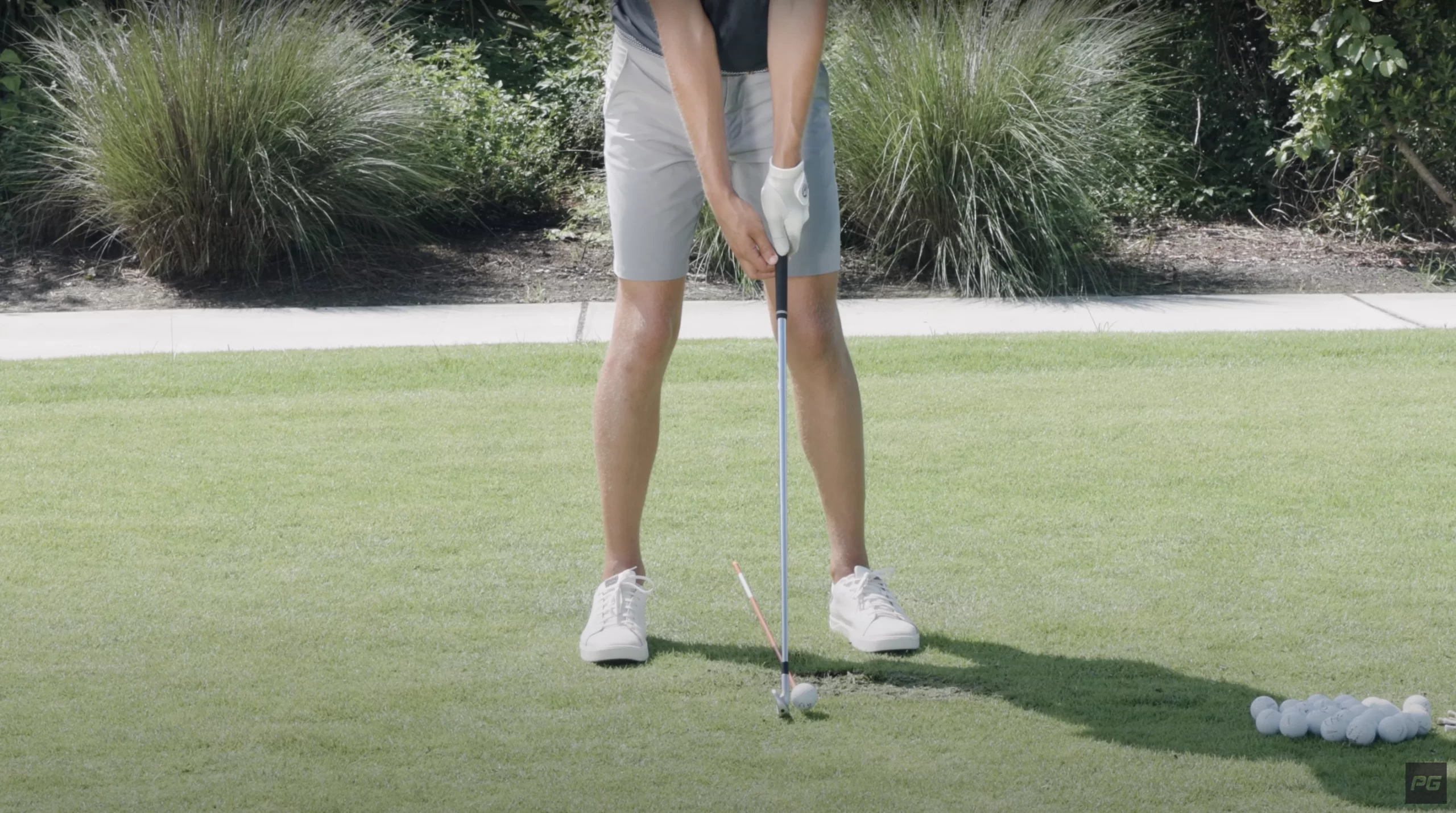 Golfer holding a stick to the ground with an alignment stick under him